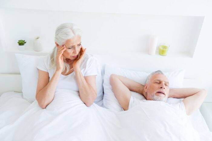 woman holds her ears while man next to her snores in sleep sleep apnea dentist in Nixa Missouri